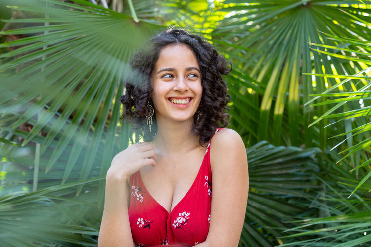 Portrait of young woman standing against palm tree