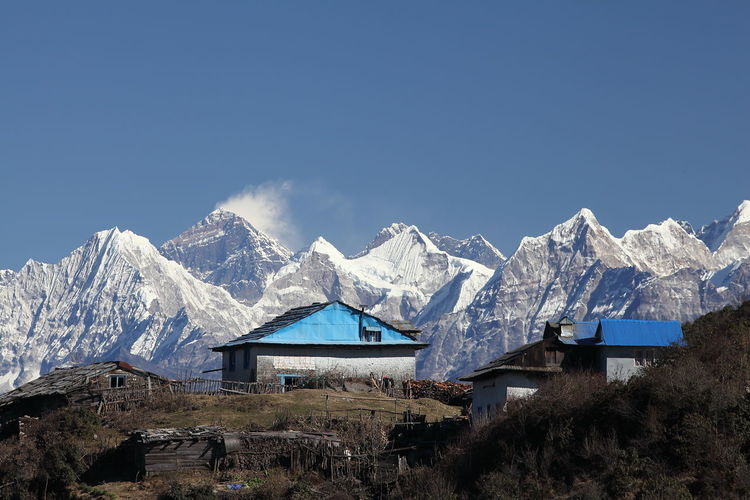 Cottages and snowcapped mountains against clear sky