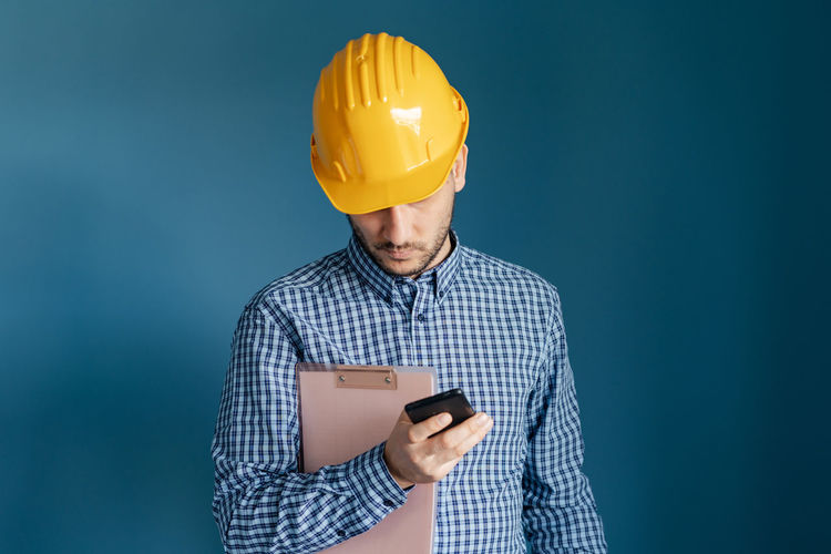 Engineer using mobile phone against blue background