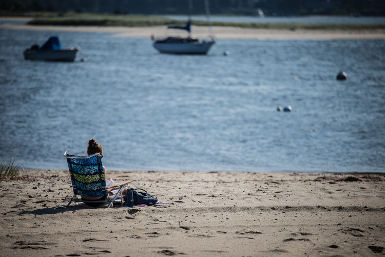 Rear view of woman sitting on beach