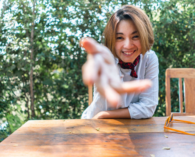 Portrait of smiling woman gesturing while sitting outdoors