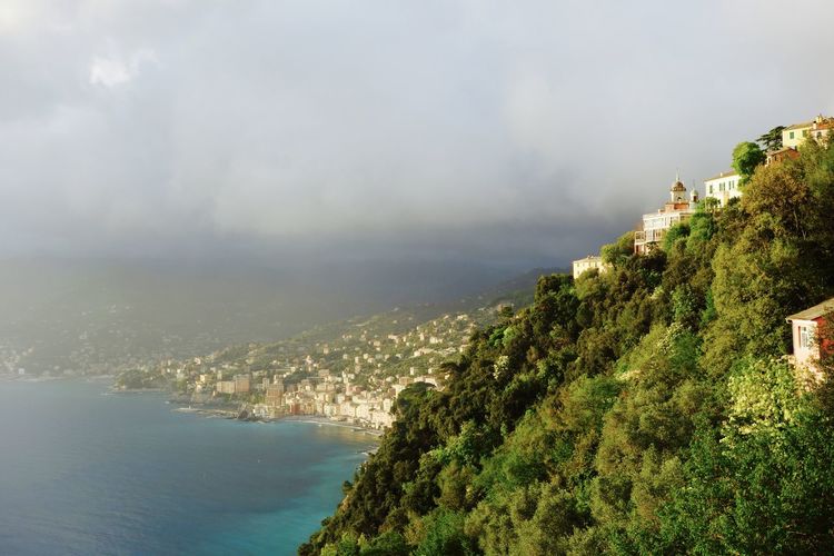 Scenic view of mountains by sea against cloudy sky at camogli