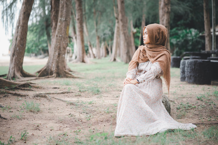 Young woman wearing hijab while sitting in forest