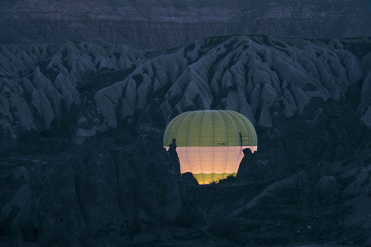 Illuminated hot air balloons amidst mountain at night