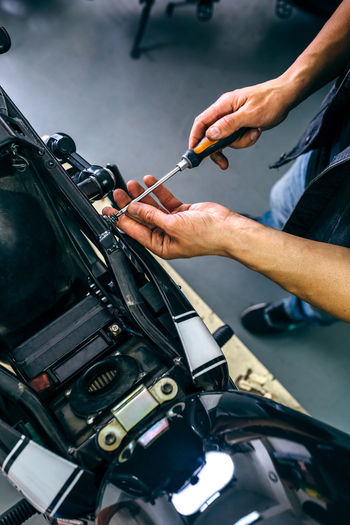 Mechanic repairing customized motorcycle in the workshop Hands Man Mechanic Motor Motorcycle Repairing Bike Biker Builder Caucasian Ethnicity Custom Custom Bikes Customized Garage Male Motor Vehicle Motorbike One Person Professional Screwdriver Top View Unrecognizable Person Vertical Vintage Work Bench