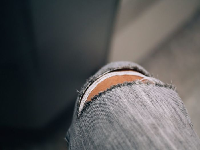 Close-up of person wearing torn jeans
