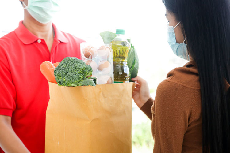 Woman wearing mask taking delivery of vegetables at home
