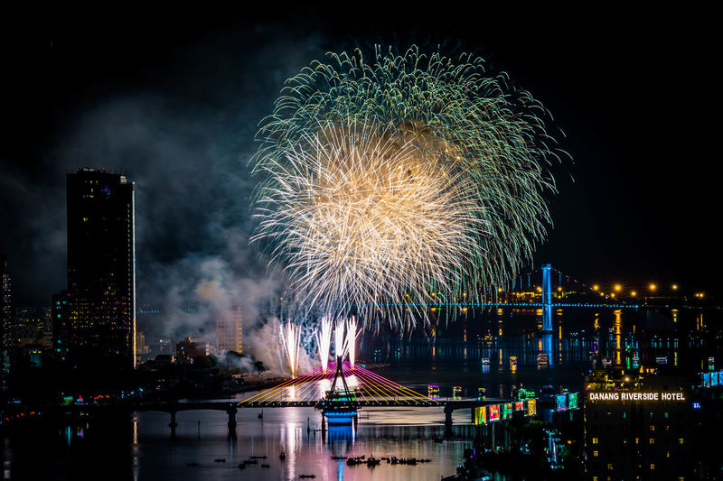 Firework display over river against sky