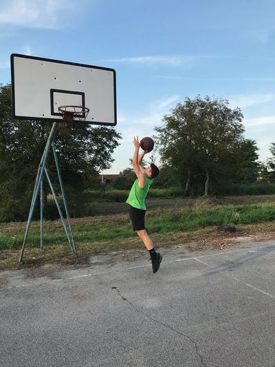 Man playing with basketball hoop against sky