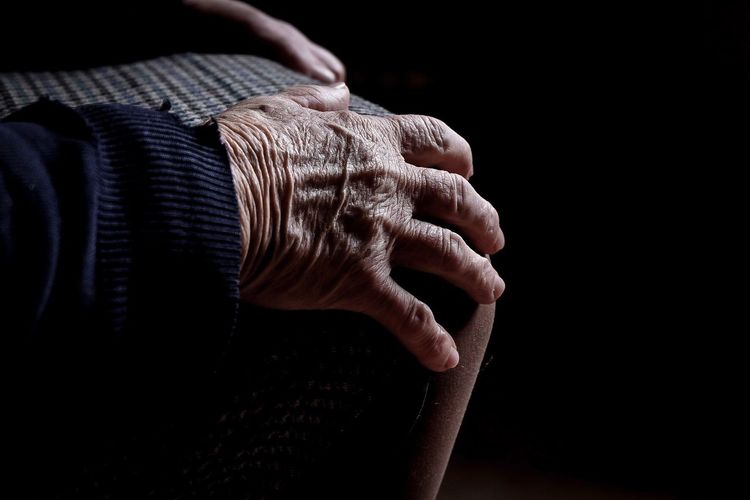 Midsection of senior woman sitting over black background