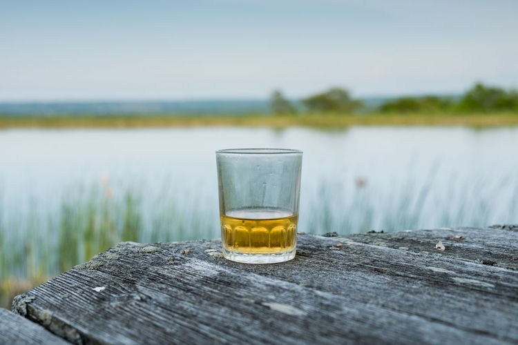 Close-up of drink on table by lake