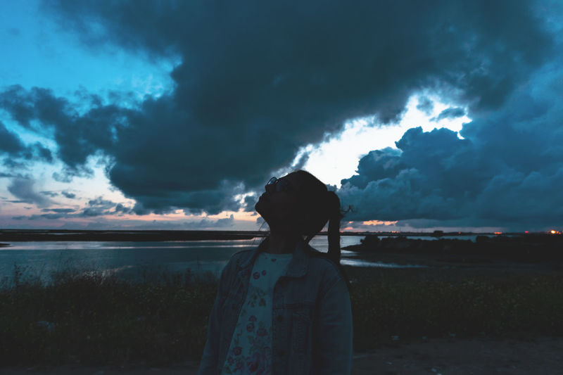 Young woman looking towards cloudy sky