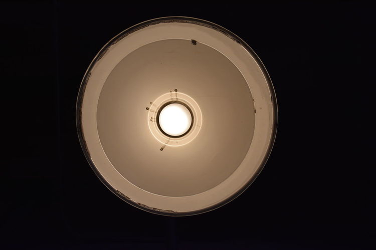 Low angle view of illuminated light bulb in darkroom