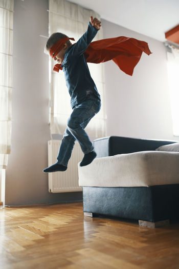 Little boy dressed up as a superhero playing at home