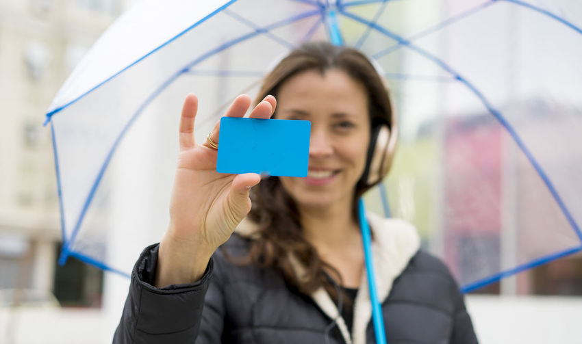 Woman showing business card while holding umbrella