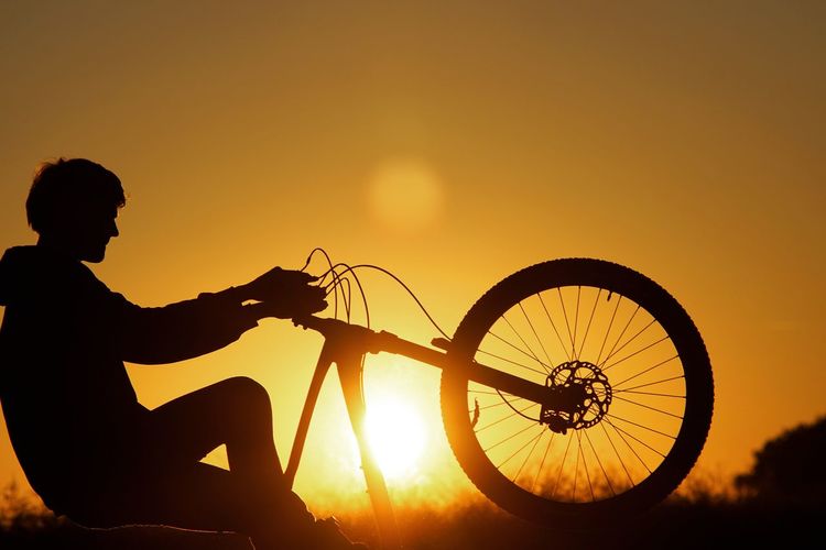Silhouette man cycling against sky during sunset