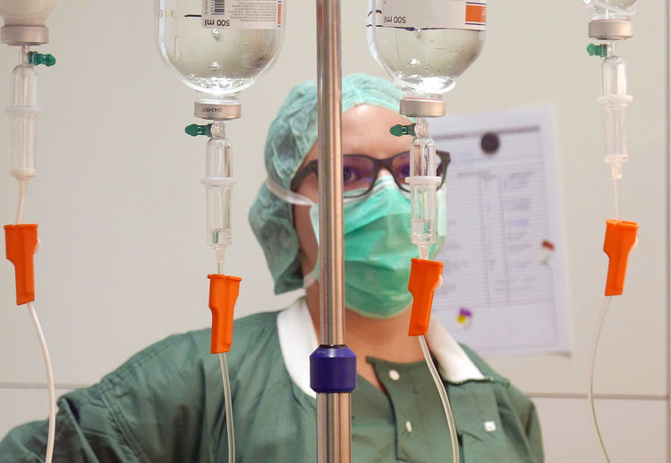 Female doctor standing by iv drips hanging at hospital
