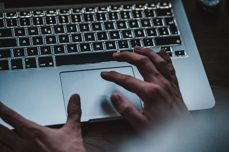 Cropped image of person using laptop on desk