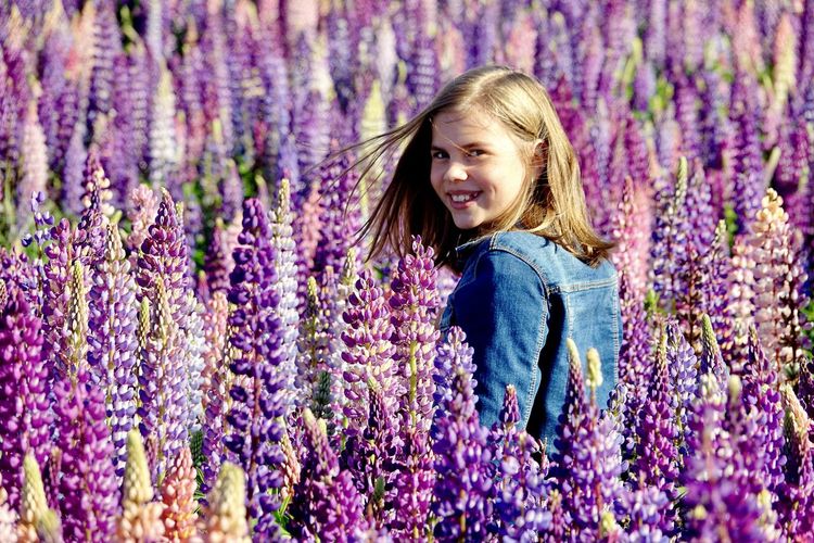 Portrait of smiling girl with purple flowers on field