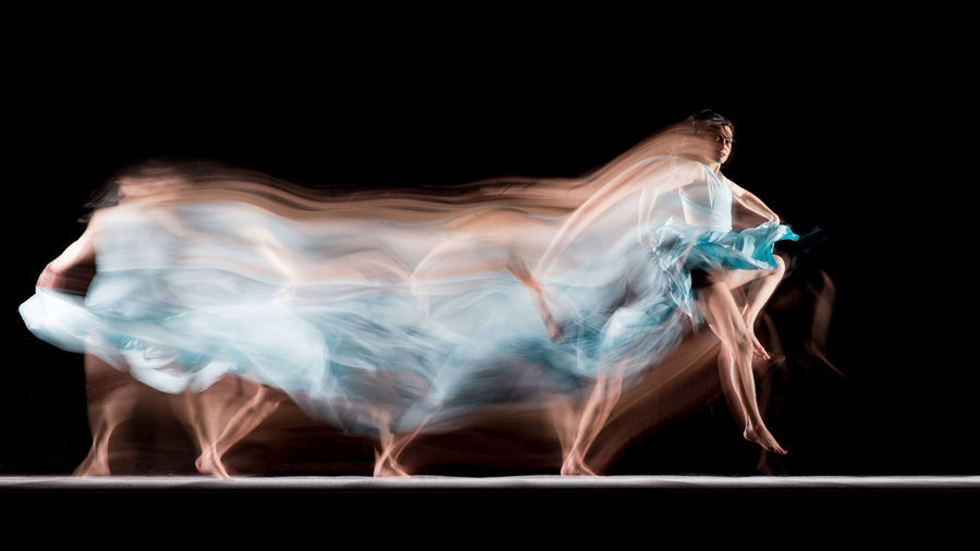 Blurred image of woman dancing against black background