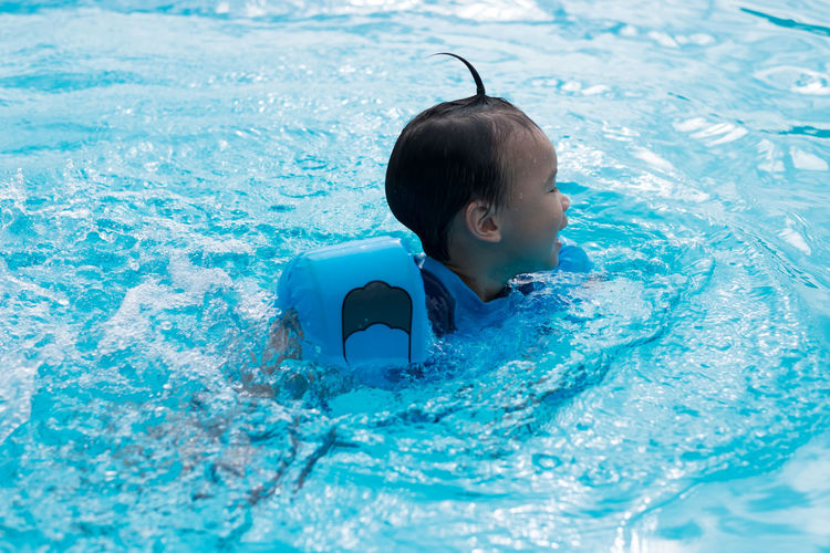 Boy wearing water wings while swimming in pool