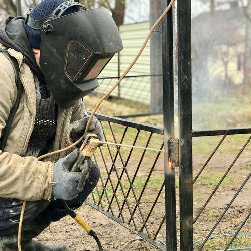 A welder welds a fence on the street