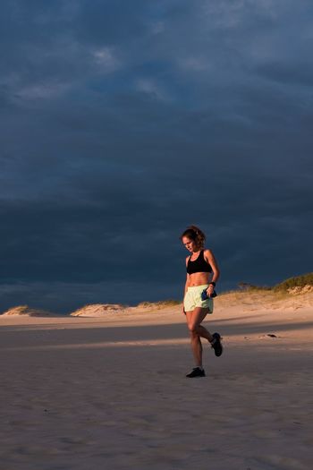 Woman running on beach against sky