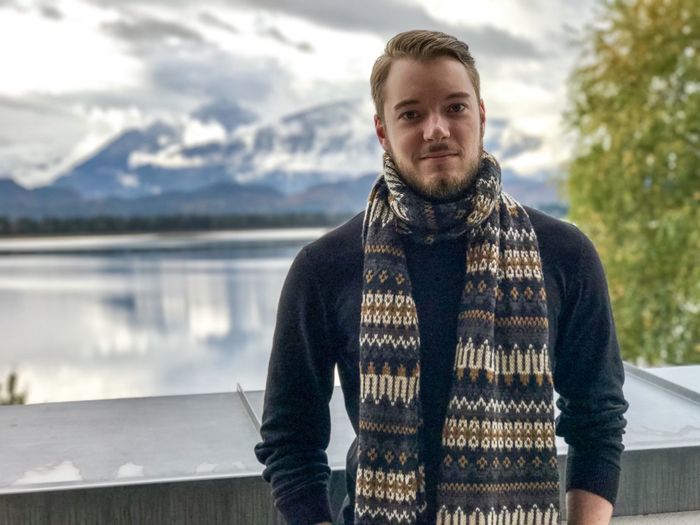 Portrait of handsome young man wearing muffler against lake