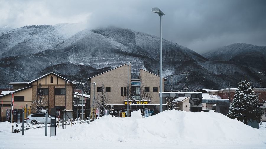 Snow covered houses by mountain against sky