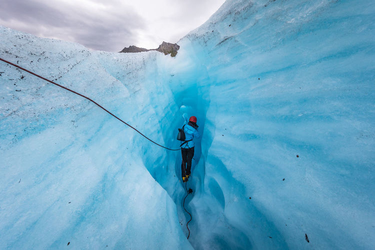 Rear view of person walking in ice cave