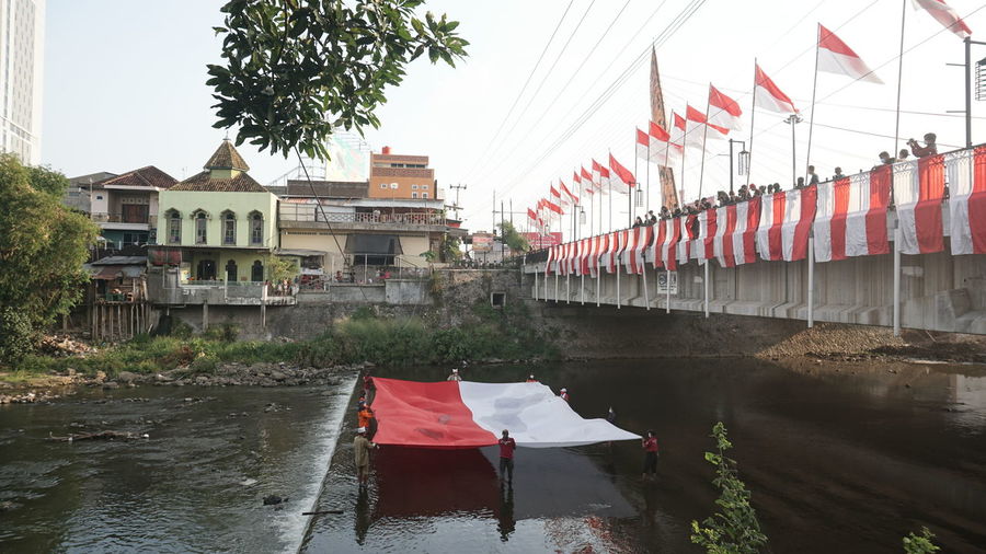 Flag by river against buildings in city