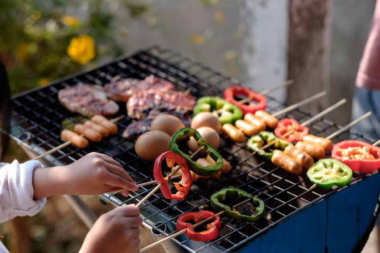 Cropped image of girl cooking food on barbecue in yard