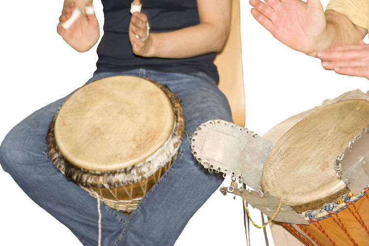Midsection of people playing drum against white background
