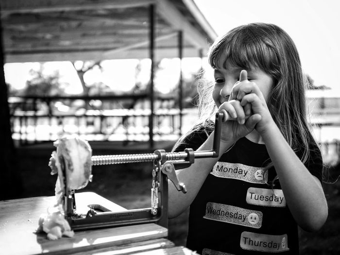 Cute girl holding fruit peeler on table outdoors