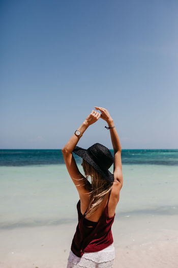 Rear view of woman at beach against clear sky