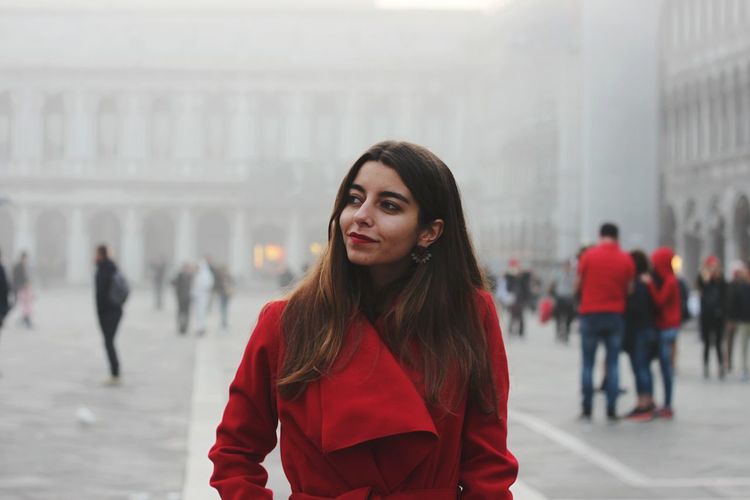 Woman wearing red dress while standing in city during winter