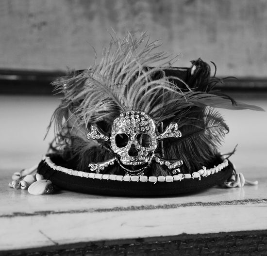 Close-up of hat with feathers and decorative skull on table