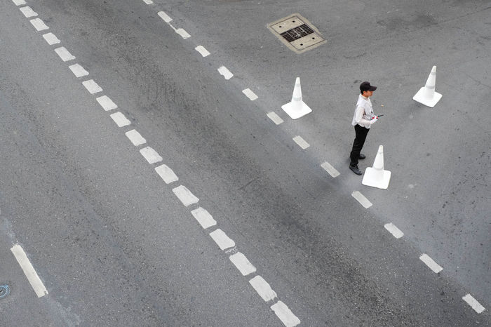 HIGH ANGLE VIEW OF TWO PEOPLE STANDING IN THE ROAD
