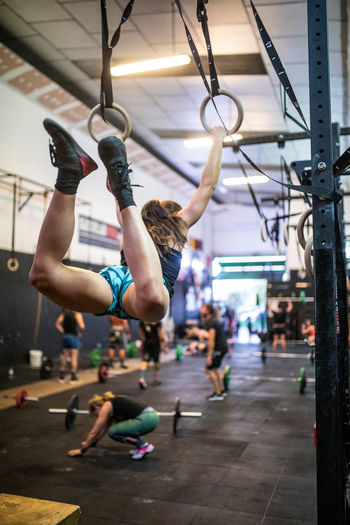 Sportswoman training on gymnastic rings in modern gym
