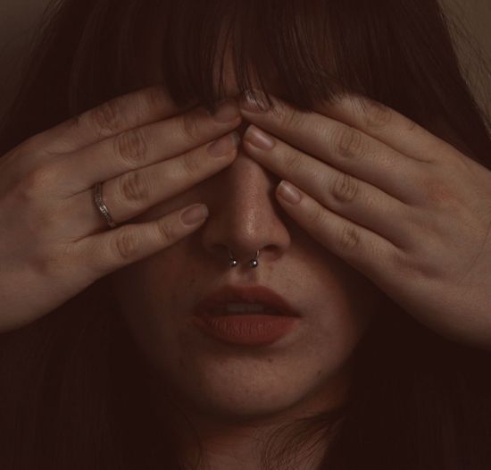 Close-up of woman with hands covering eyes