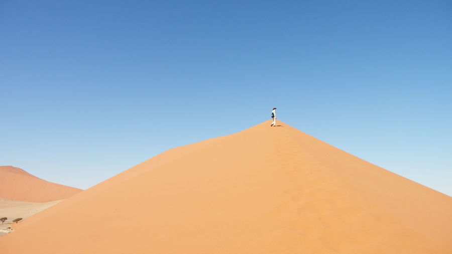 Low angle view of person standing on sand dune at namib desert