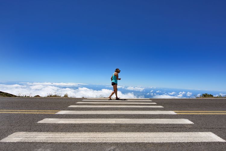 Woman walking on highway at haleakala against blue sky