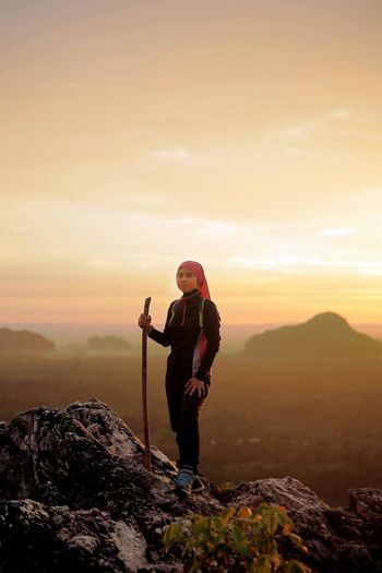 Portrait of woman standing on rock against sky during sunset