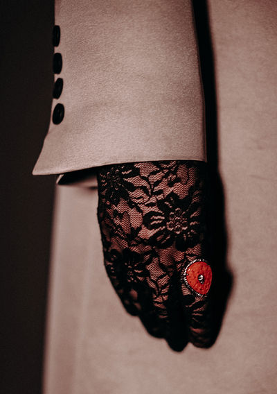 Signet ring with red stone, lace and black gloves and beige women's coat with black buttons