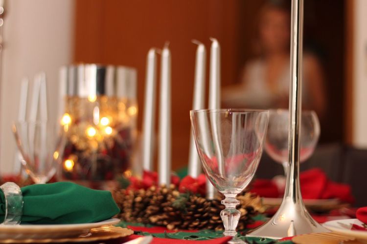 Close-up of wineglasses with candles and pine cones on dining table during christmas