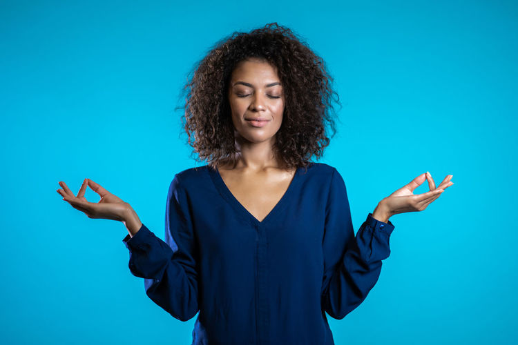 Young woman standing against blue background