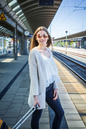 Full length of woman standing with luggage at railroad station platform