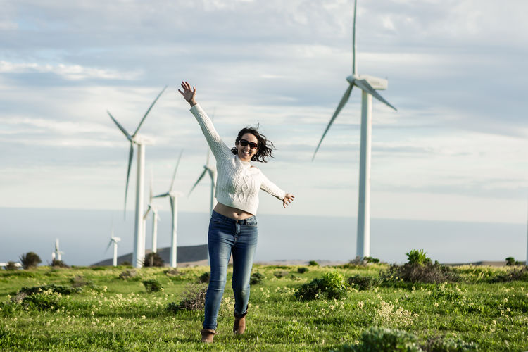 Full length of young woman standing on field against sky