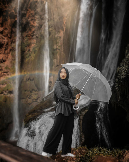 Girl standing by waterfall in forest