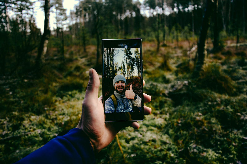 Cropped hand of man taking selfie in forest